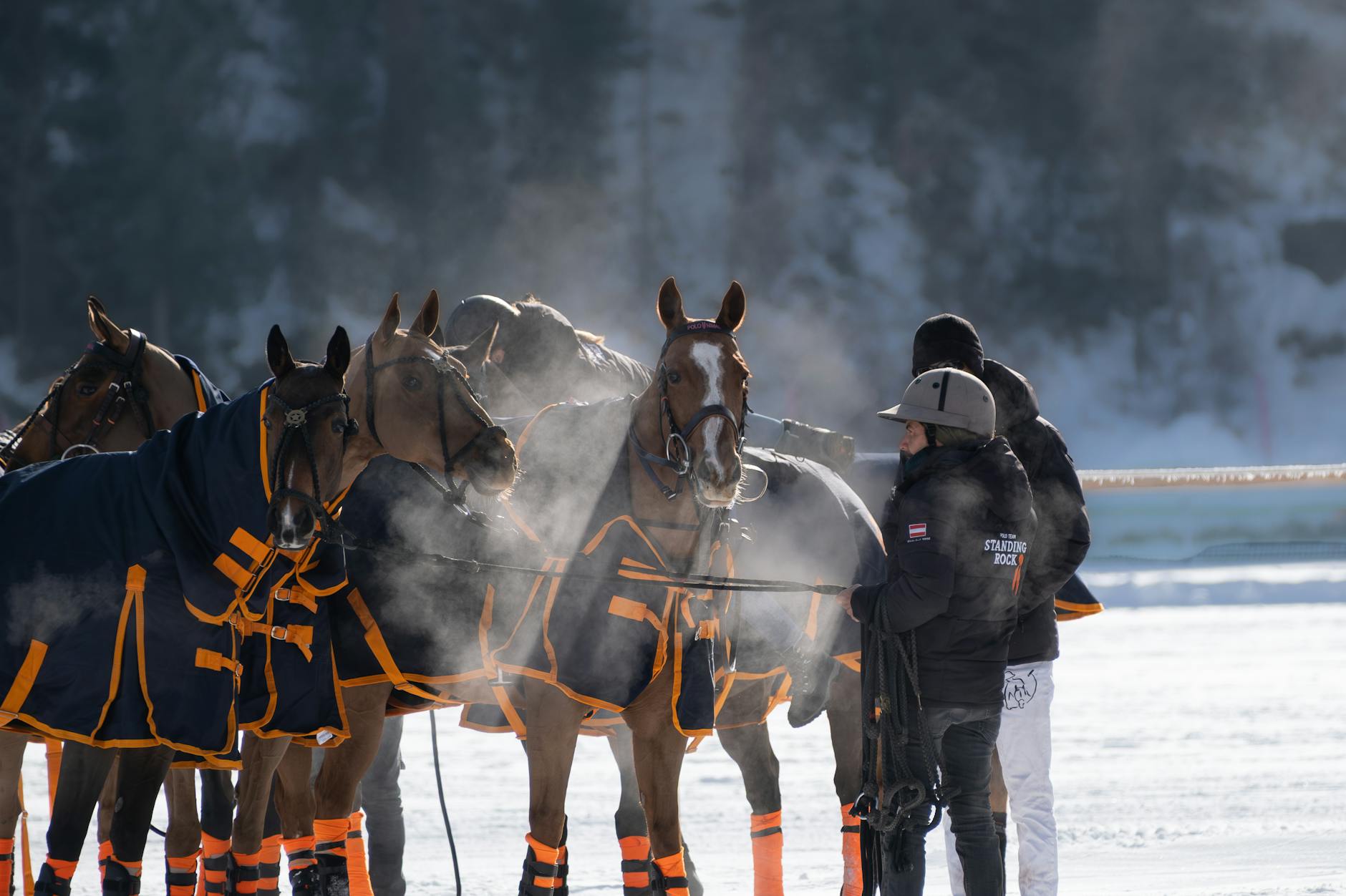 Jeźdźcy na koniach w zimowych derkach przed startem na śniegu
