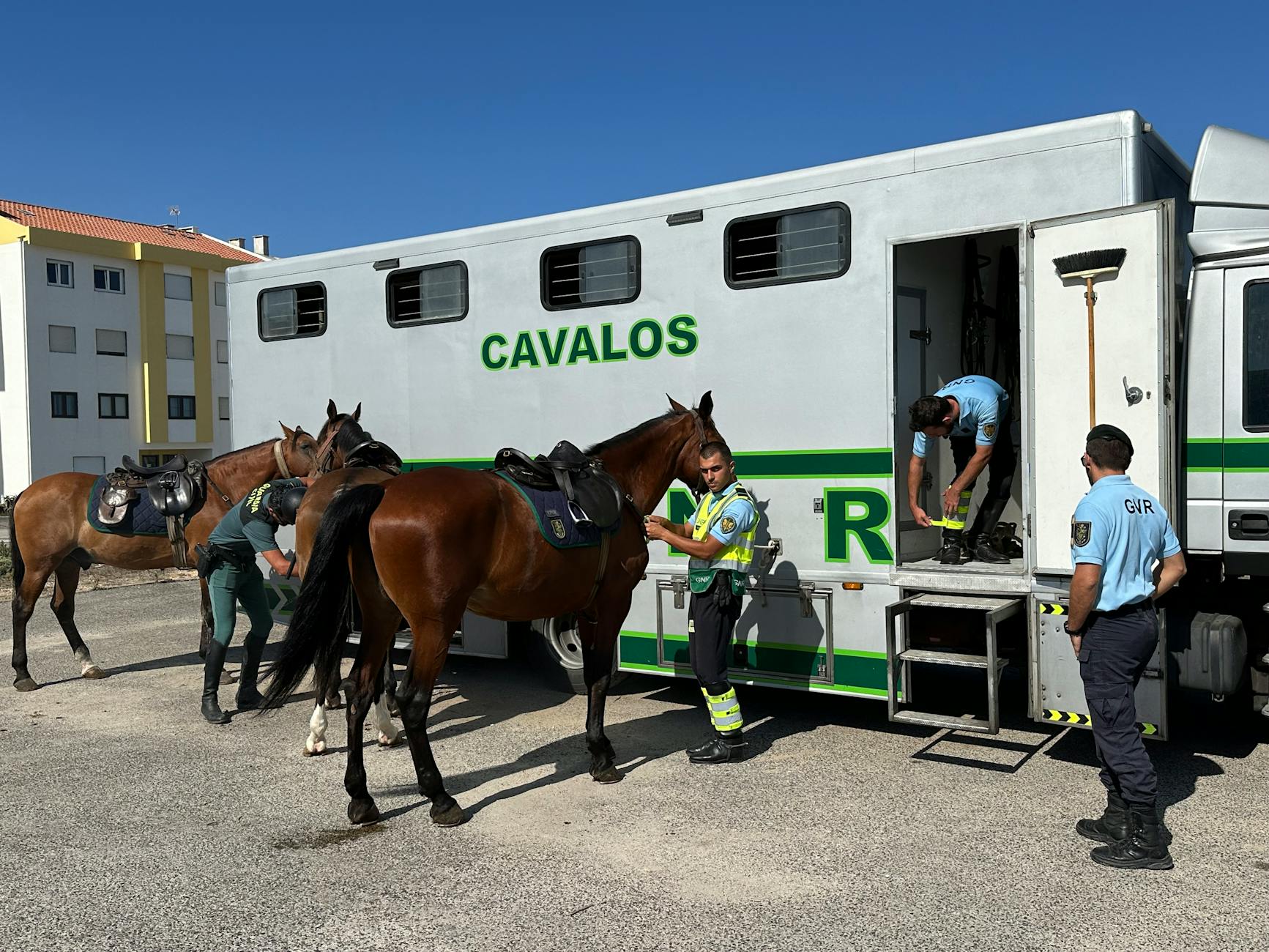 Policjanci siadający na osiodłane konie przed wyjazdem na wydarzenie