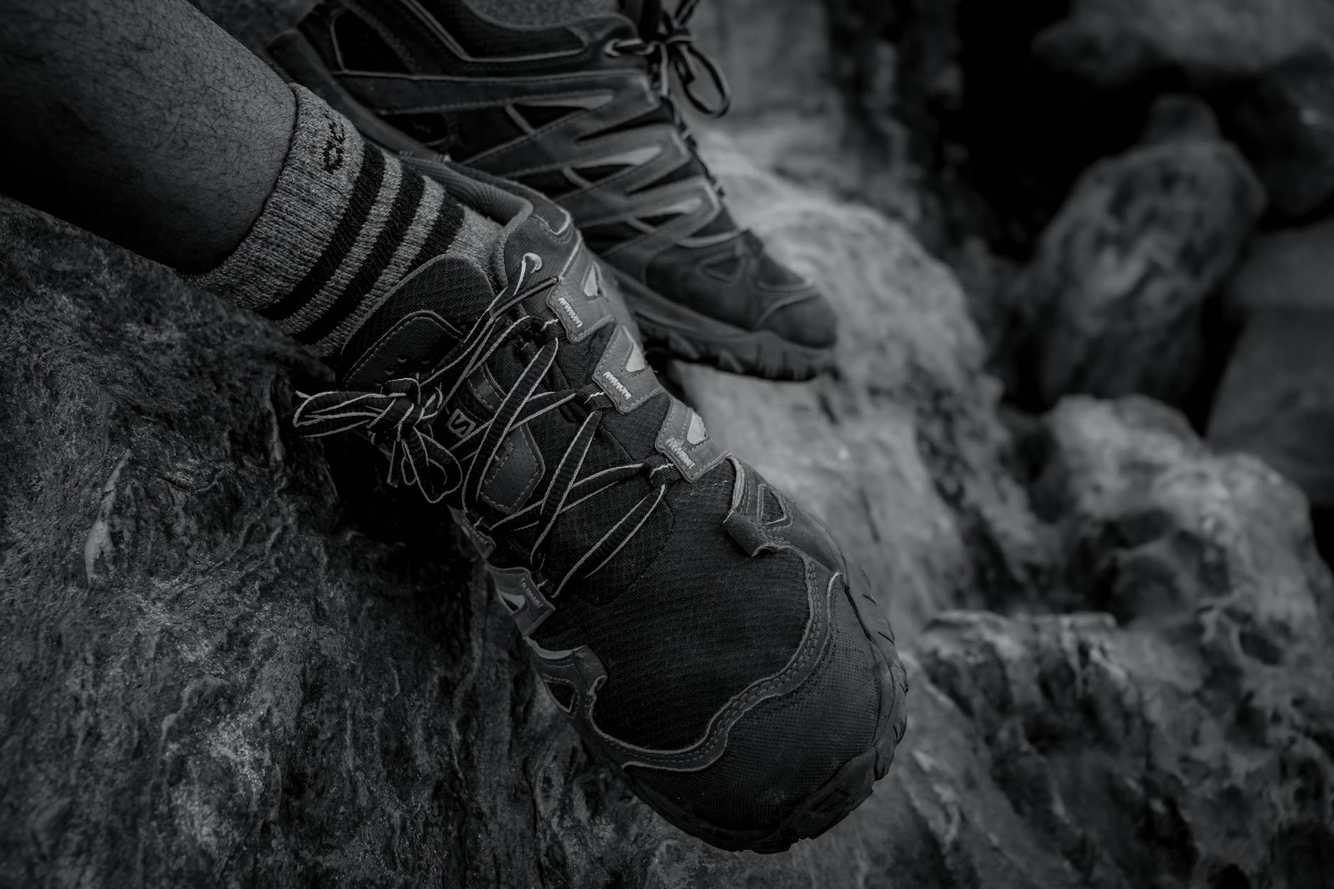 Buty trekkingowe na skalistym terenie w czarno-białym zbliżeniu