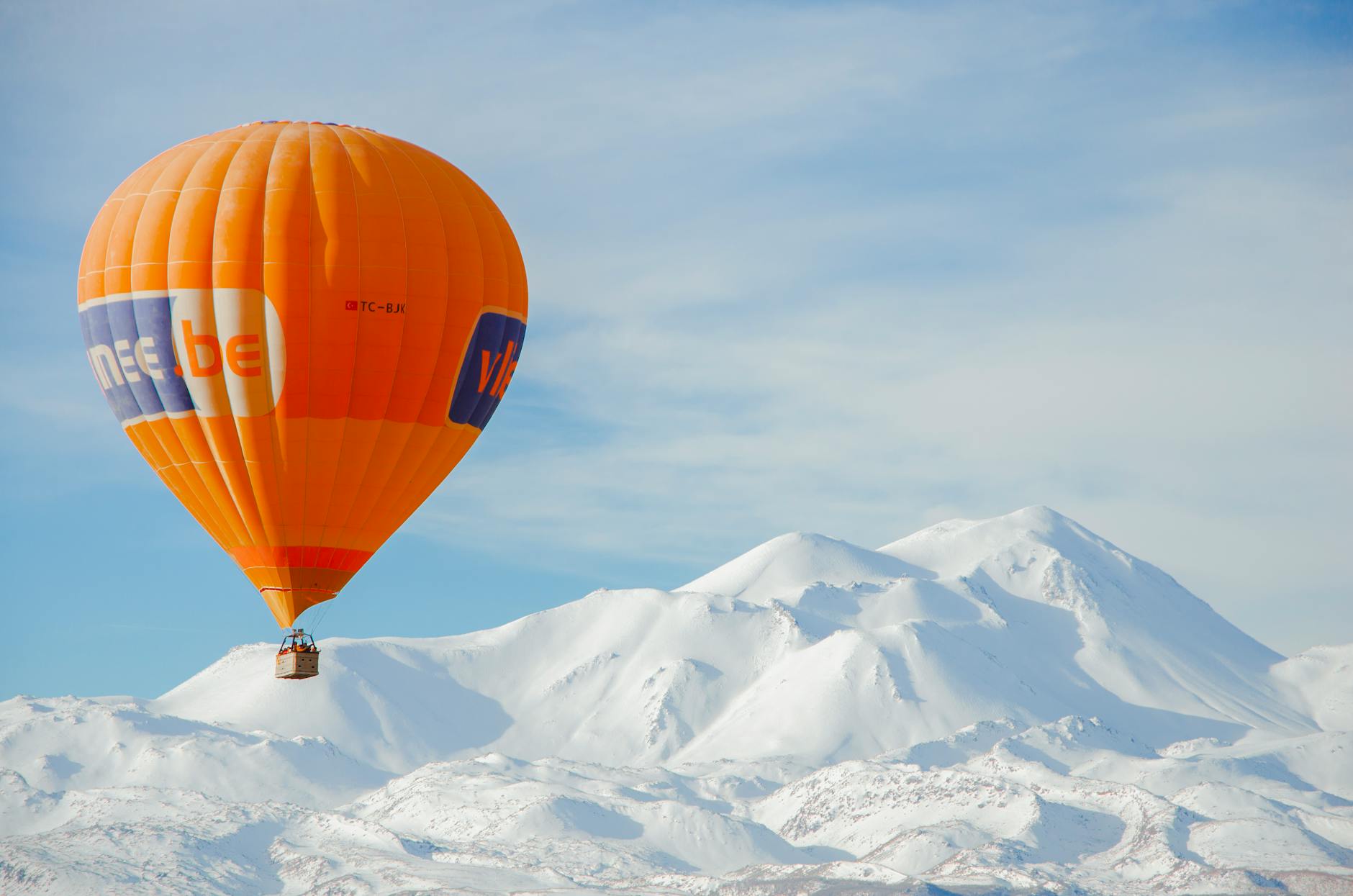 Pomarańczowy balon nad ośnieżonymi górami w Turcji