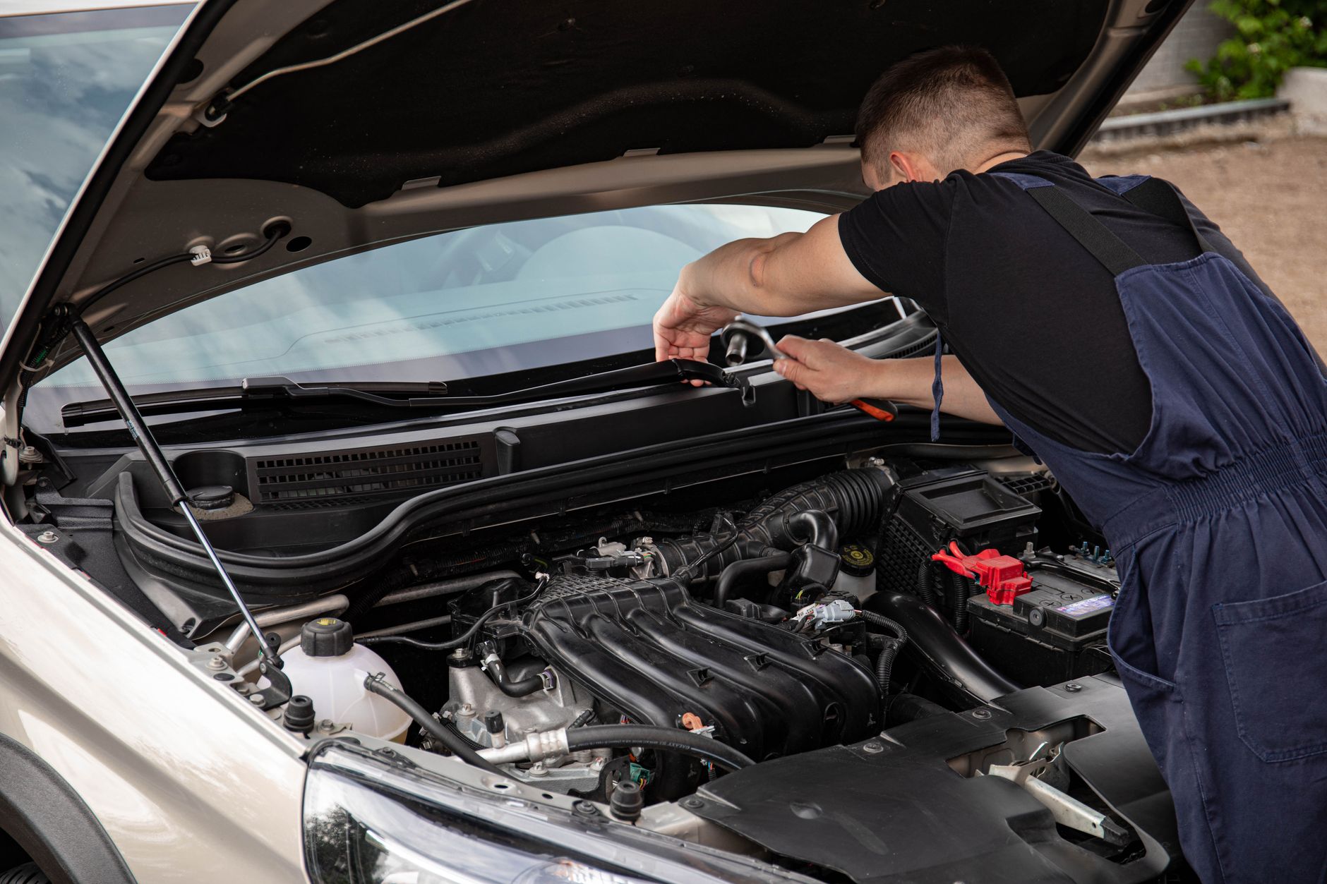 Mechanik naprawia silnik samochodu na zewnątrz w słoneczny dzień