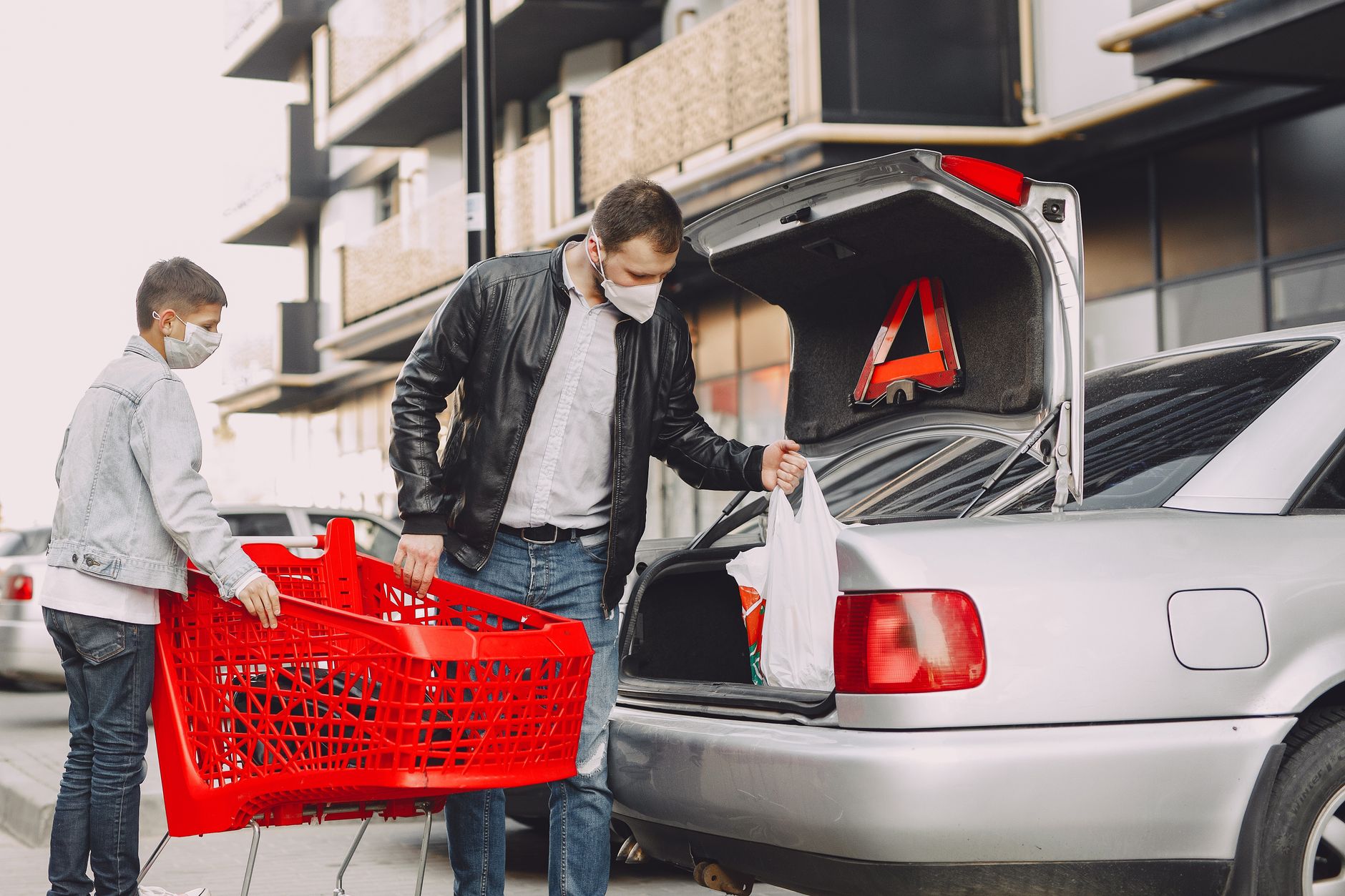 Ojciec i syn pakują zakupy do bagażnika auta na parkingu